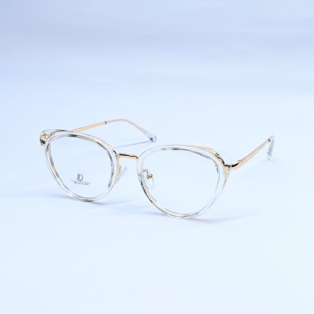 Oversized oval eyeglasses with a clear acetate frame and gold metal rims, displayed on a light blue gradient background.