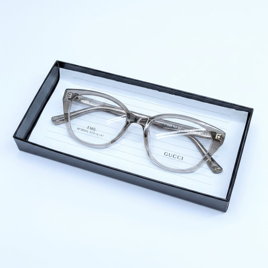 Gucci eyeglasses in a translucent smoky brown acetate, presented inside a black gift box with a white lined insert.